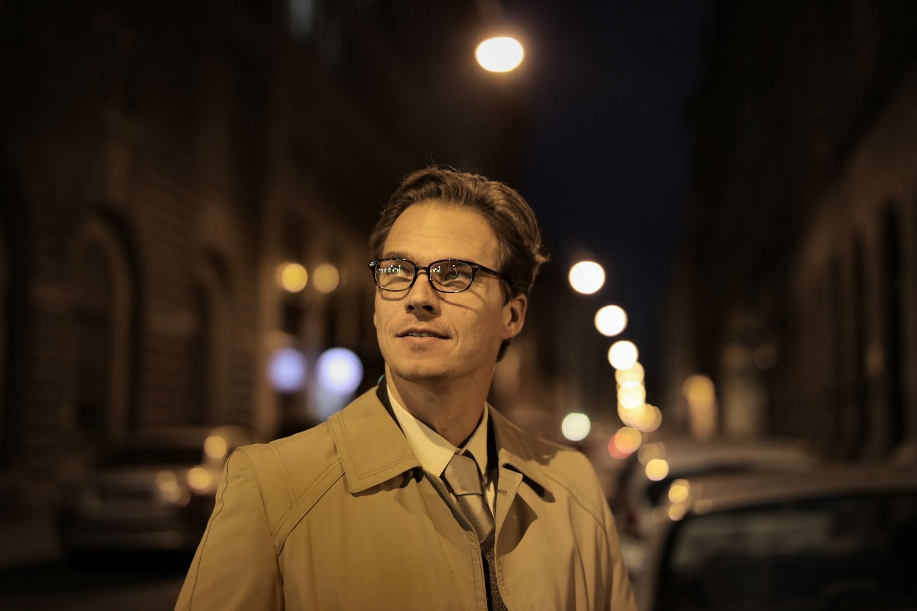 Well-dressed man in eyeglasses standing on a city street, confident and sharp